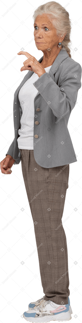 Seitenansicht einer alten dame im anzug, die eine kleine größe von etwas zeigt