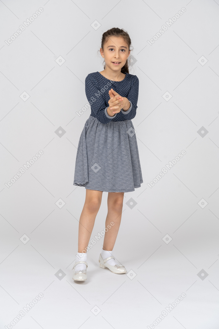 Vista frontal de uma garota fazendo uma arma de dedo com um sorriso