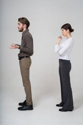 Side view of a questioning young couple in office clothing