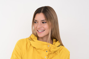 Gilr in a yellow raincoat watching at something on the side