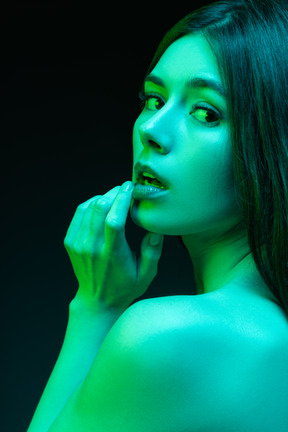 Close-up a sensual portrait of young woman touching her lips in neon lights
