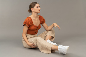 Young woman sits with raised hand