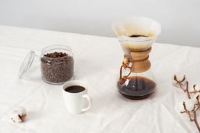 Chemex, taza de café y jarra con granos de café.