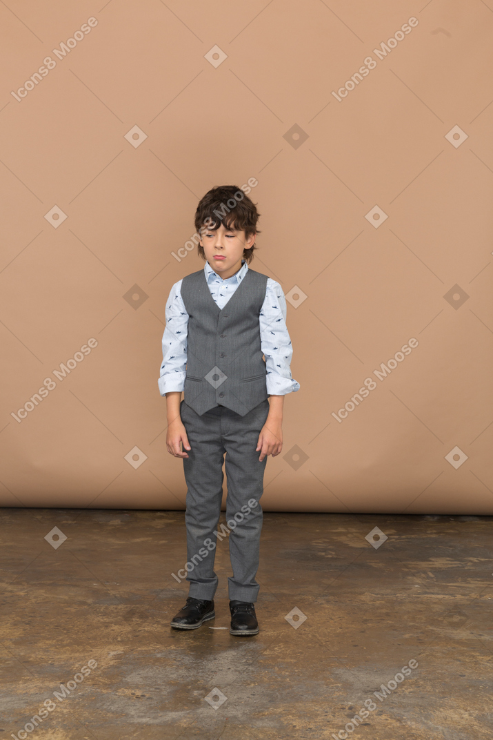 Vista frontal de um menino de terno cinza parado