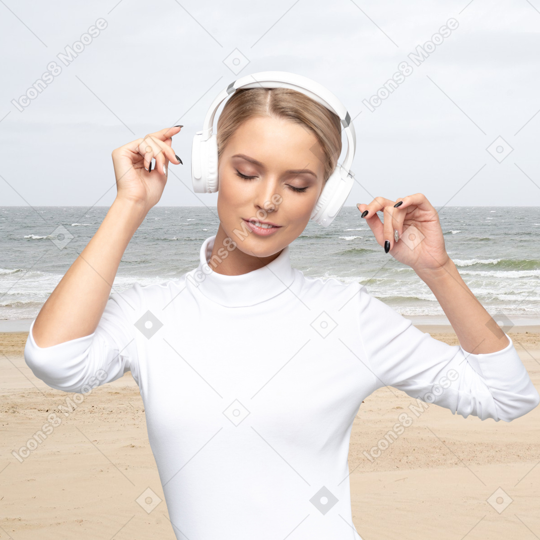ビーチでヘッドフォンで音楽を楽しむ女性
