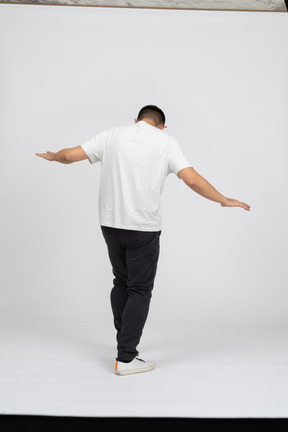 Back view of a man in casual clothes walking with outstretched arms