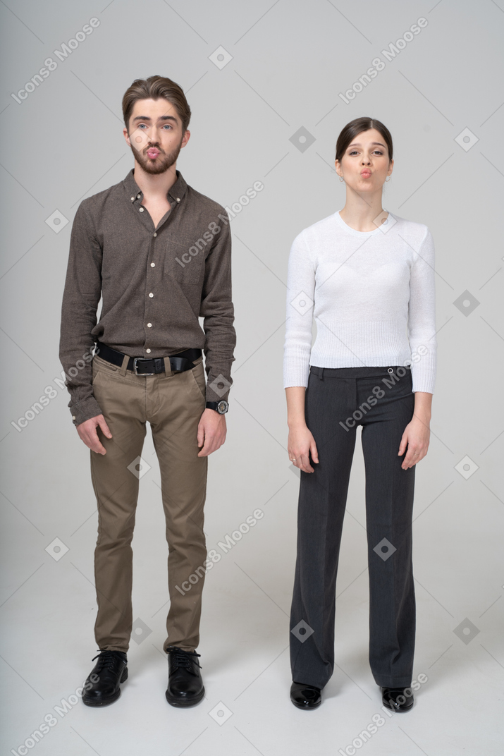 Vista frontal de una joven pareja haciendo pucheros en ropa de oficina