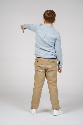 Vista trasera de un niño mostrando el pulgar hacia abajo
