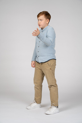 Menino de pé em uma camisa azul falando e gesticulando