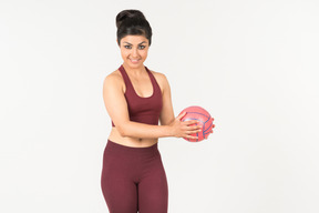 Souriante jeune femme indienne tenant une boule rose