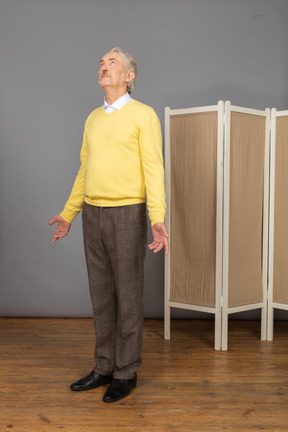 Three-quarter view of an old man looking up while outspreading hands