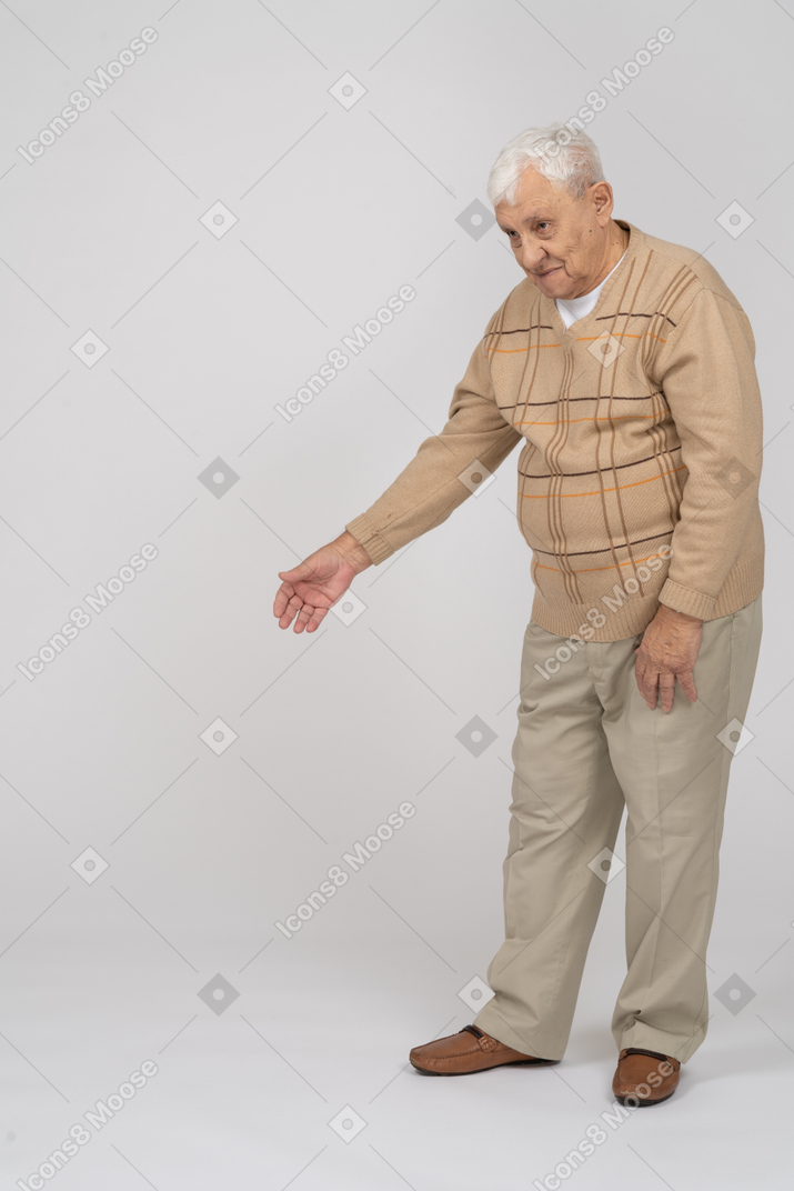 Vorderansicht eines alten mannes in freizeitkleidung, der mit ausgestrecktem arm steht