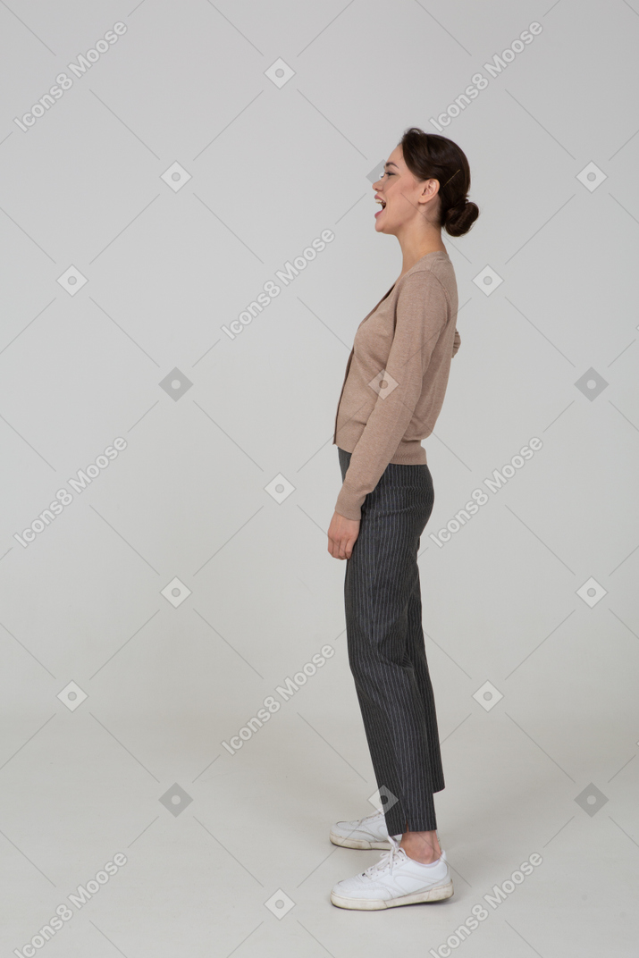 Side view of a laughing female in pullover and pants putting hand on hip