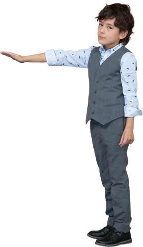 Vista laterale di un ragazzo in abito grigio in piedi con il braccio teso