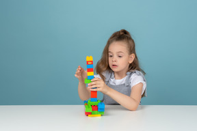 A little girl holding a toy tower from falling