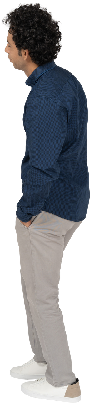 Vista laterale di un uomo in abiti casual in piedi con le mani in tasca