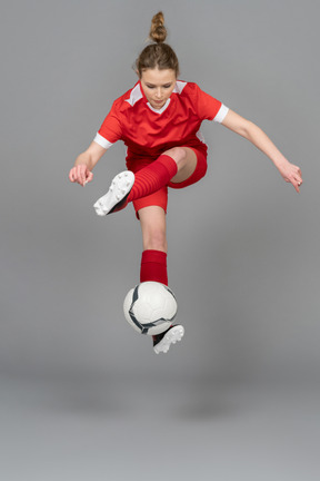 A sporty young woman jumping with ball