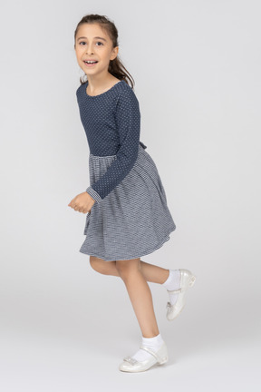 Little girl in blue dress and white shoes running