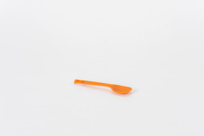 Cuillère en plastique orange sur fond blanc