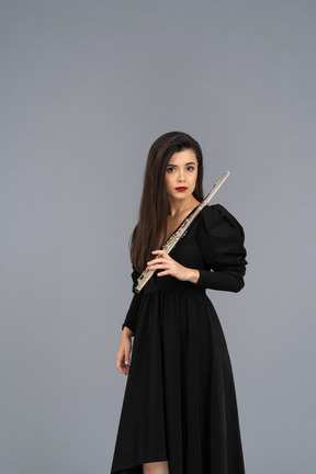 Three-quarter view of a serious young lady in black dress holding flute