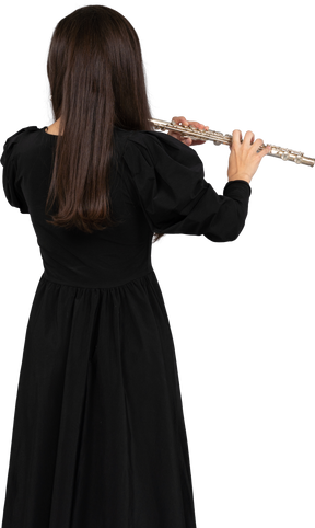 Schwarze ansicht einer jungen dame im schwarzen kleid, die flöte spielt