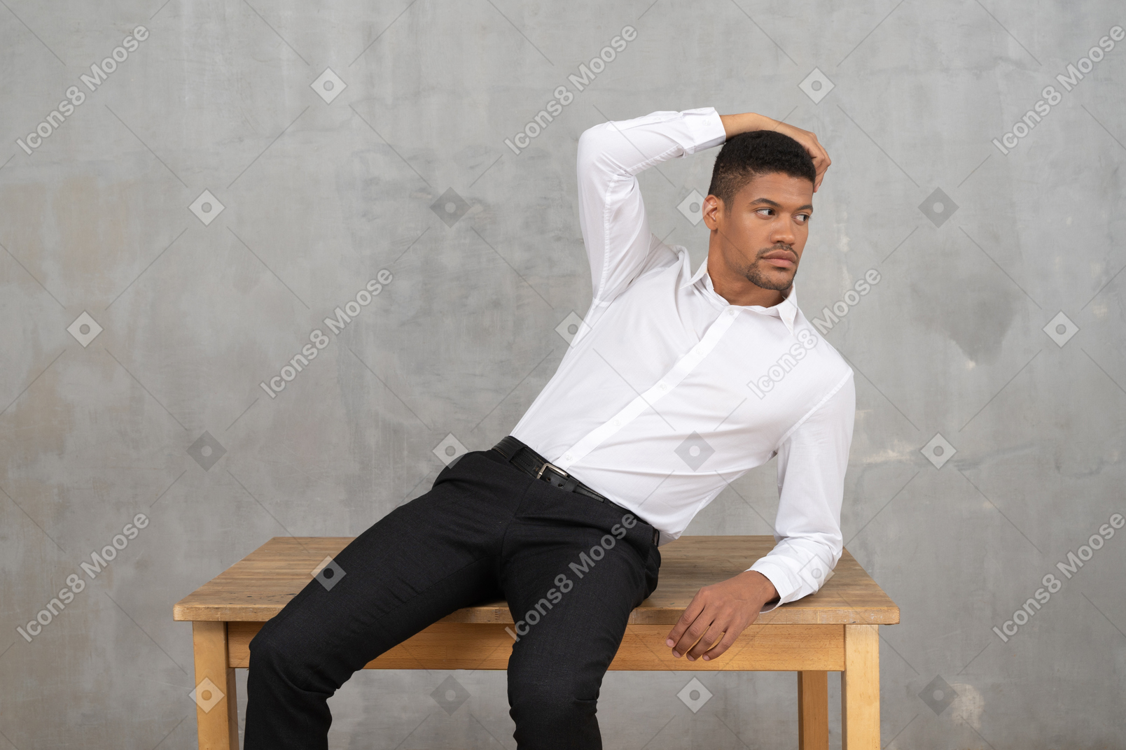 Uomo in abiti da ufficio seduto su un tavolo e in posa