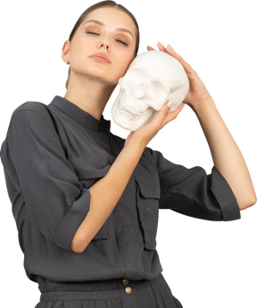 Front view of a young woman in a jumpsuit holding a plaster skull