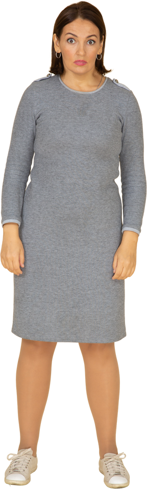 Vista frontal de uma mulher em um vestido cinza em pé com os braços cruzados