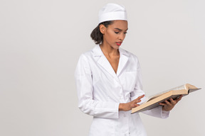 Medico femminile attraente che cerca qualcosa in un libro