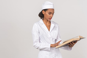 Attractive female doctor looking for something in a book