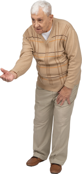 Vista frontale di un vecchio in abiti casual in piedi con il braccio teso e spiegando qualcosa