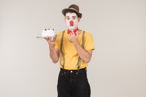 Male clown tasting a cake he's holding