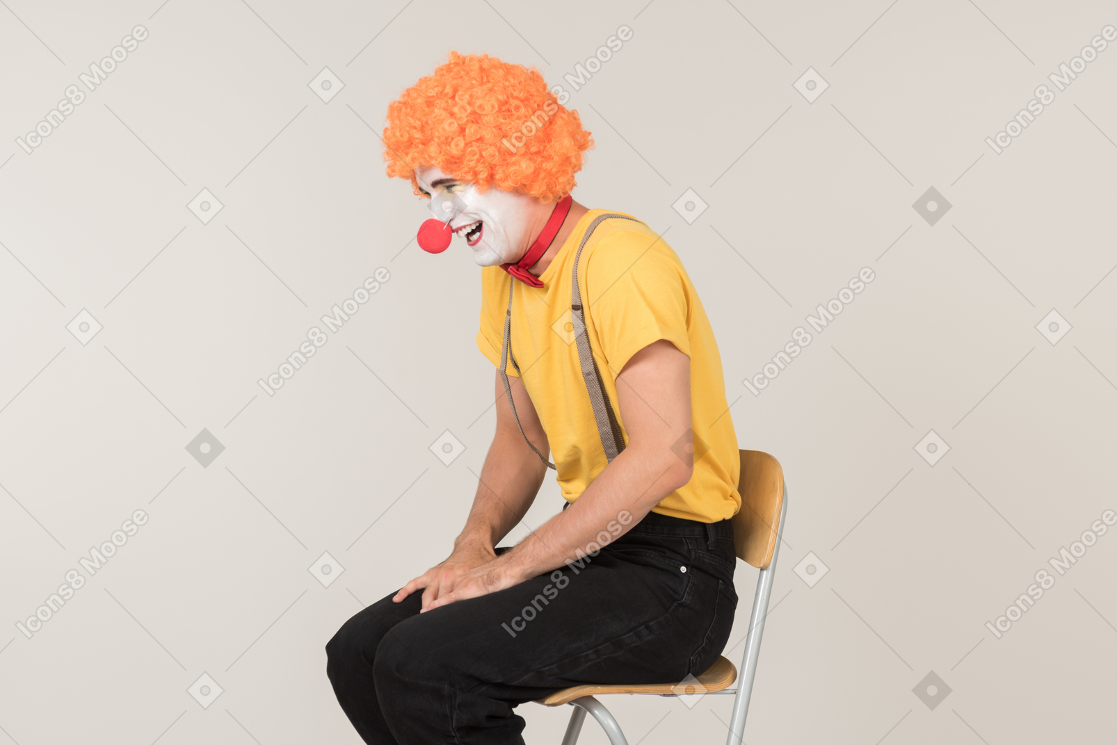 Sad looking male clown sitting on the chair and crying