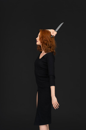 A side view of the beautiful young woman posing with a knife