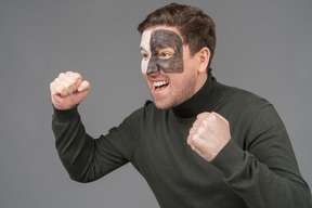 Three-quarter view of a screaming male football fan clenching fists