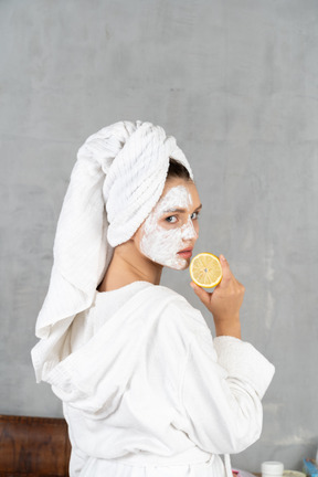 Back view of a woman in bathrobe holding a lemon