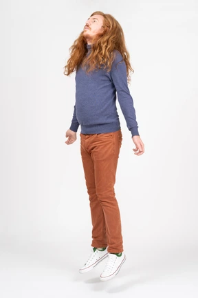 Side view of a young man in casual clothes jumping