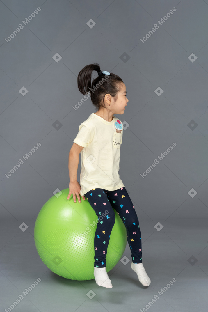 坐在绿色健身球上的小女孩