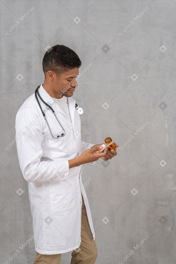 Jeune médecin versant des pilules sur sa main