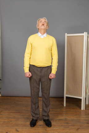 Front view of an impatient old man clenching fists while looking up