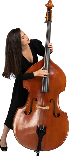 Front view of a young woman in black dress playing the double-bass and leaning forward