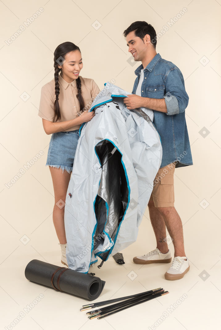 Young asian woman and caucasian man building a tent