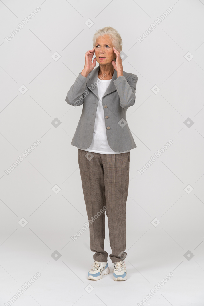Front view of an old lady in grey jacket touching her face