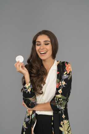Pretty arab woman laughing out loud with her eyes closed and cotton pad in hand