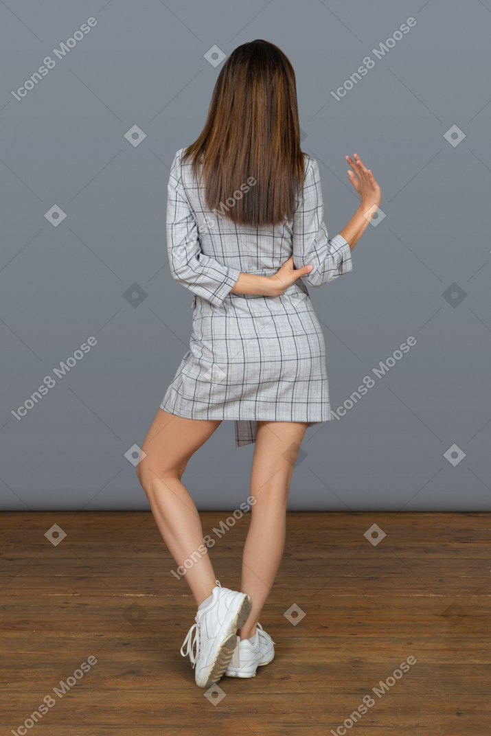 Unrecognizable slim brunette woman waving with a hand back to camera