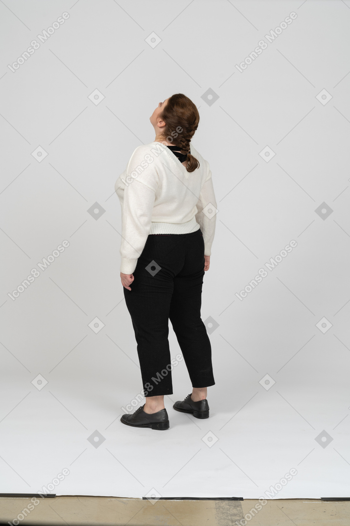 Rear view of a plump woman in casual clothes looking up