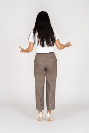 Vista posterior de una joven quejándose en calzones y camiseta extendiendo sus manos