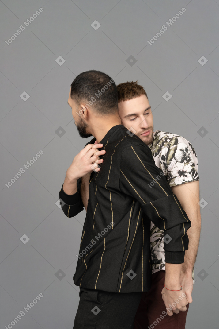 Close-up of two men back hugging and intertwining hands