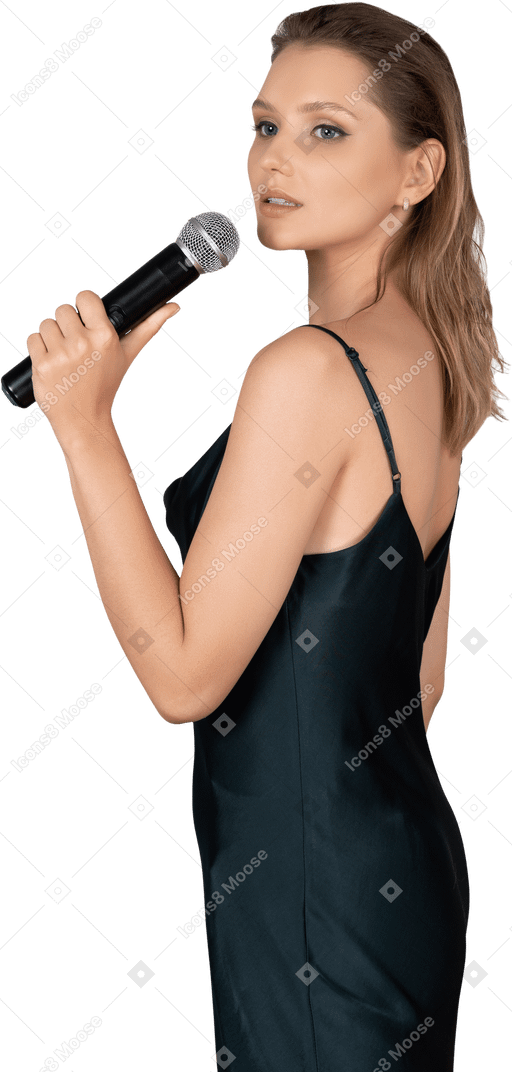 Vue latérale d'une jeune femme en robe de nuit tenant un microphone