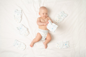 Baby boy in diaper lying among diapers